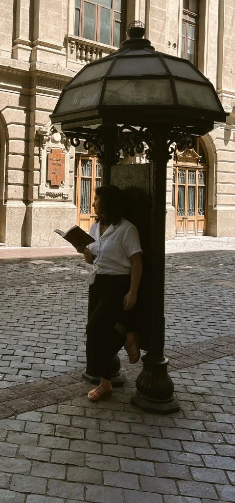 Apoyada en un farol, con un libro abierto