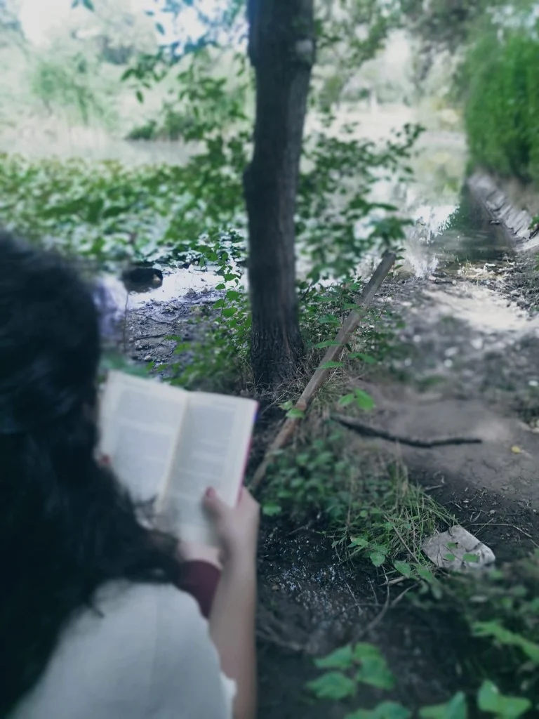 Leyendo de espaldas, junto al agua